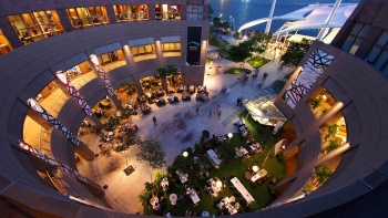 滨海艺术中心外观鸟瞰视图，人们聚集在地面层餐馆及户外广场区享用晚餐。