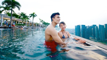 一对情侣在白天从滨海湾金沙空中花园的无边际泳池里眺望新加坡天际线