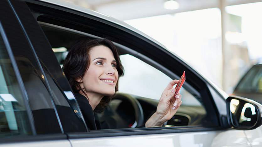 カードを手に持って車内から外を眺める女性