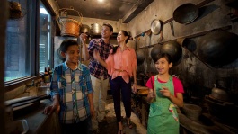 年轻家庭在牛车水原貌馆 (Chinatown Heritage Centre) 内参观仿造 19 世纪五十年代的共用厨房