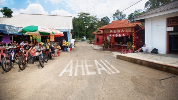 Rustic street side stalls and shrines line a street on the island of Pulau Ubin