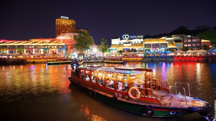 夜里，驳船停靠新加坡河，远景可见亮起的克拉码头标志