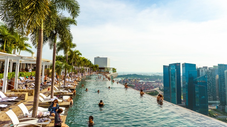 日光映照下，从滨海湾金沙空中花园的无边际泳池俯瞰新加坡天际线。