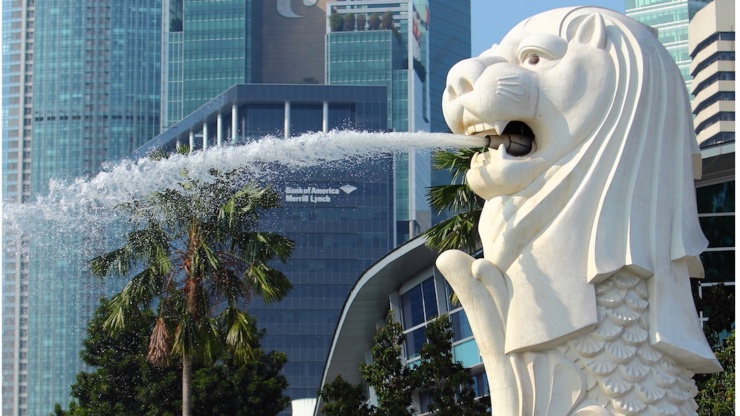 白天鱼尾狮喷水的竖拍照片，背景是新加坡天际线
