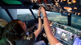 女士在新加坡飞行体验 (Flight Experience Singapore) 中坐在飞行员座位上摆弄控制面板按钮的摆拍照片
