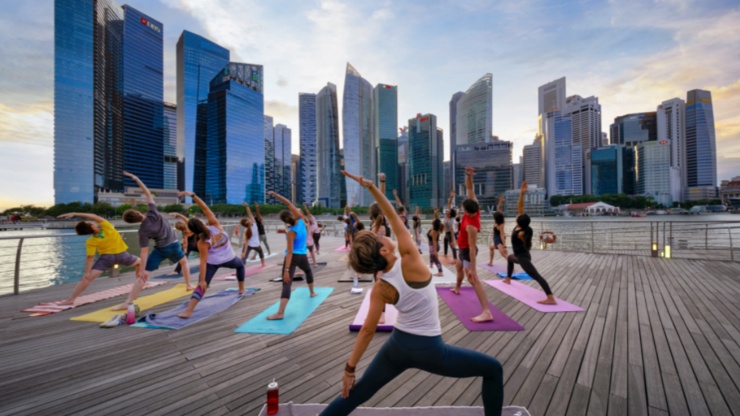 一群人以新加坡市区天际线为背景，静心练瑜伽