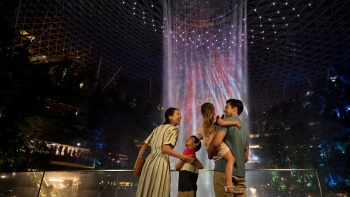 带着两个孩子的一家人在欣赏星耀樟宜的汇丰银行雨漩涡