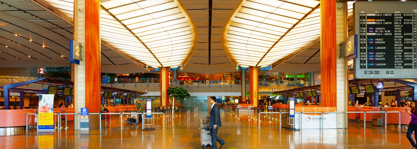 身着西装、手持行李的男子在新加坡樟宜机场经过行李与机票柜台处